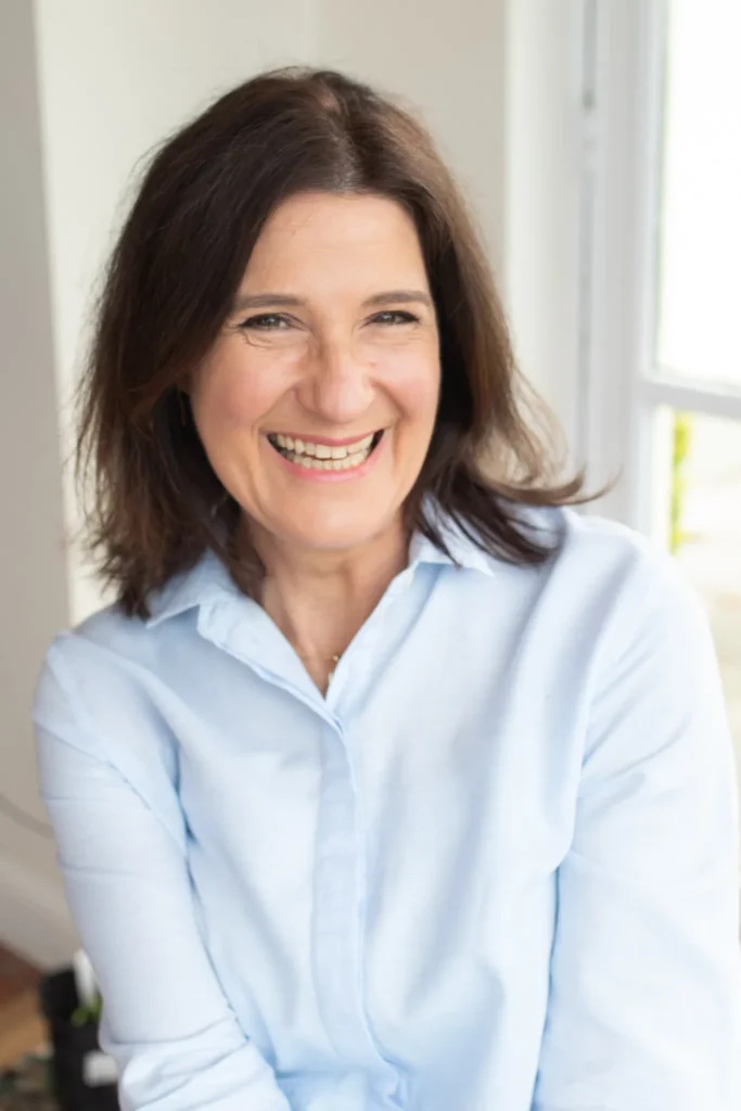 A woman in a light blue shirt sitting indoors near a bright window, highlighting a professional and organized workspace in County Wicklow.